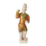 A Chinese pottery figure of a standing groom Ming dynasty Wearing an amber and green glazed tun...