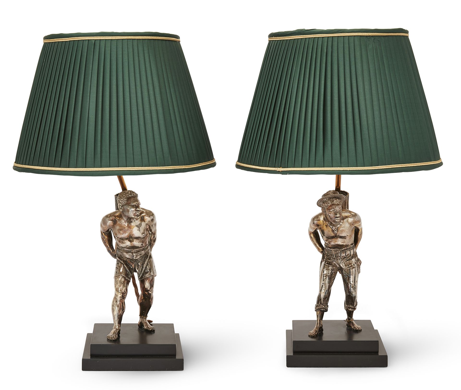 Two silvered brass figural table lamps, 20th century, each figure modelled bare foot carrying a b...