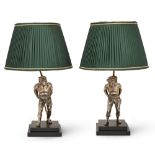 Two silvered brass figural table lamps, 20th century, each figure modelled bare foot carrying a b...