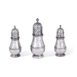 A set of three Queen Anne Britannia silver sugar casters by Charles Adam, London, two 1712, one w...