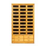 An English light oak haberdashers cabinet, early 20th century, with twenty seven glass fronted sh...