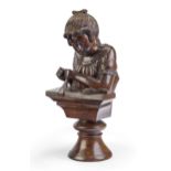 A hardwood sculpture of a girl sewing, late 19th century, depicted with her hands holding a sewin...