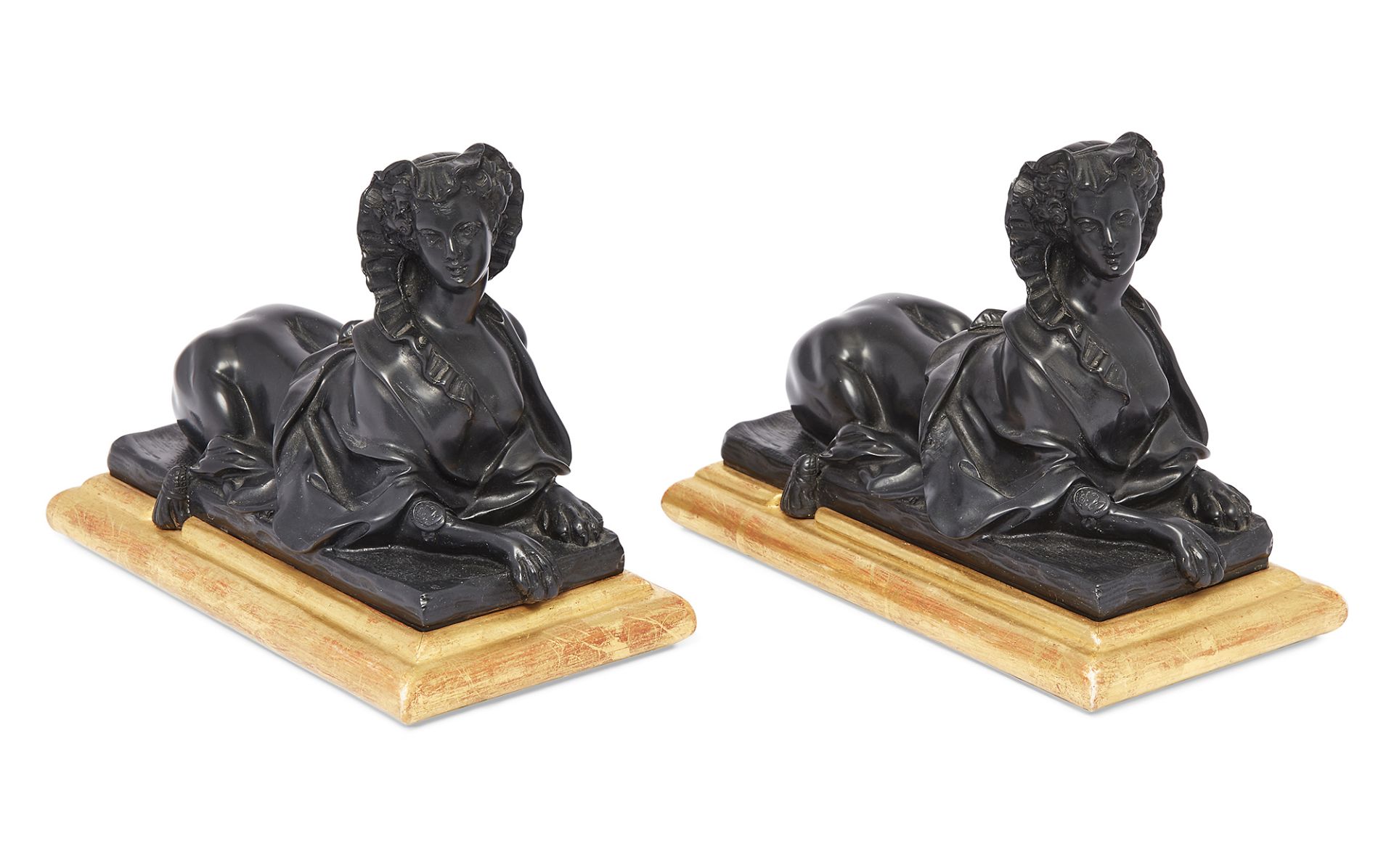 Two modern ebonised resin recumbent female sphinxes, of Louis XVI style, on giltwood bases, 17cm ...