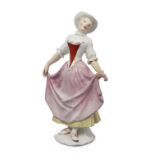 A Meissen figure of Columbine, c.1748, probably modelled by J.J. Kändler, in a dancing pose, wear...