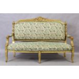 A French giltwood sofa, Louis XV style, 20th century, with cream ground upholstery with green flo...