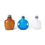 Three Chinese glass snuff bottles, late Qing dynasty, the first of amber hue, with paired mask an...