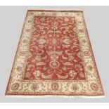 A modern Zeigler rug, the central field with scrolling floral design, on a red ground, contained ...