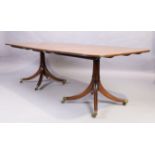An English mahogany dining table, George III style, 20th century, on twin turned column supports ...