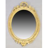 A French oval giltwood and gesso mirror, 19th century, carved wreath crest, moilded frame with ro...