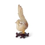 A Chinese green and russet hardstone carving of a phoenix, Republic period, the long tailed bird ...