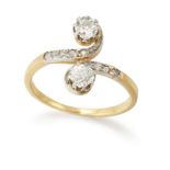 An Edwardian gold diamond crossover ring, two claw-set old European cut diamonds, to scrolling cr...