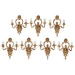 Seven French gilt-bronze twin-light wall appliques, 20th century, in the manner of Jean Hauré, th...