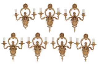 Seven French gilt-bronze twin-light wall appliques, 20th century, in the manner of Jean Hauré, th...