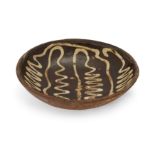 A Staffordshire slipware dish, 18th century, of circular shape with plain edge, decorated with a ...