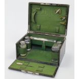 A crocodile skin travelling vanity case, enclosing a partially fitted interior with five silver t...