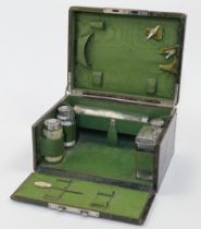 A crocodile skin travelling vanity case, enclosing a partially fitted interior with five silver t...