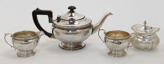 A three-piece silver tea set, comprising: a tea pot, a cream jug and a twin handled sugar bowl, B...