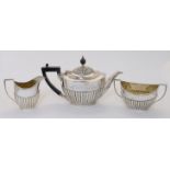 An Edwardian three-piece silver tea set, comprising: a teapot, a cream jug and a twin handled sug...