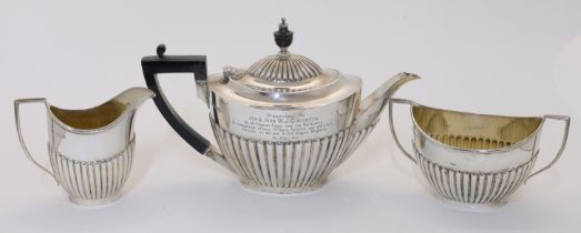 An Edwardian three-piece silver tea set, comprising: a teapot, a cream jug and a twin handled sug...