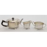 An Edwardian three-piece silver tea set, comprising: a tea pot, a cream jug and a twin handled su...