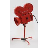A novelty red metal table lamp designed as a Hollywood Studios film projector, on tripod base, ap...