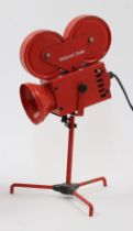 A novelty red metal table lamp designed as a Hollywood Studios film projector, on tripod base, ap...