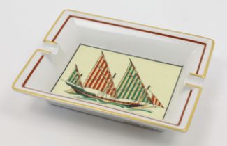 An Hermès porcelain ashtray, 20th century, decorated to the centre with a sailing yacht with gree...