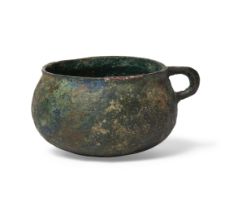 A bronze ring handled cup, possibly China, with rounded sides and flattened rim, with green and b...