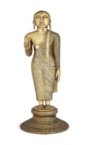A brass figure of Buddha, Sri Lanka, 19th century, solidly cast standing on a circular lotus base...