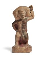 A Greek terracotta figure of a nude phallic dwarf, carrying a sack across his back, set on an int...