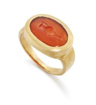 A 20th century gold, Roman cornelian intaglio ring, the oval intaglio engraved to depict a wine j...