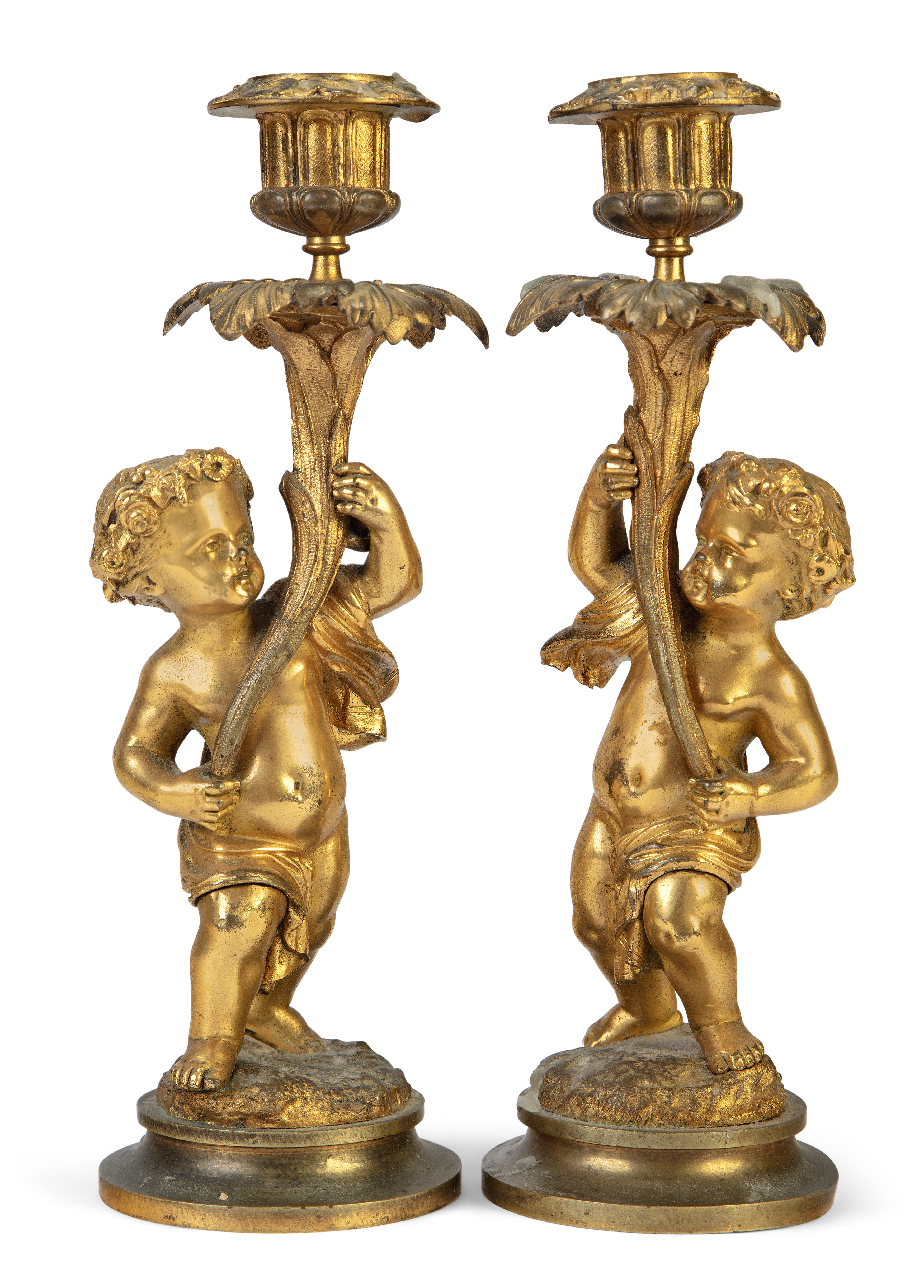 A pair of French gilt-bronze figural candlesticks, late 19th century, each modelled as a putto ho...