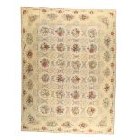 A large English needlework wall hanging, 20th century, with repeating floral sprays on a cream gr...