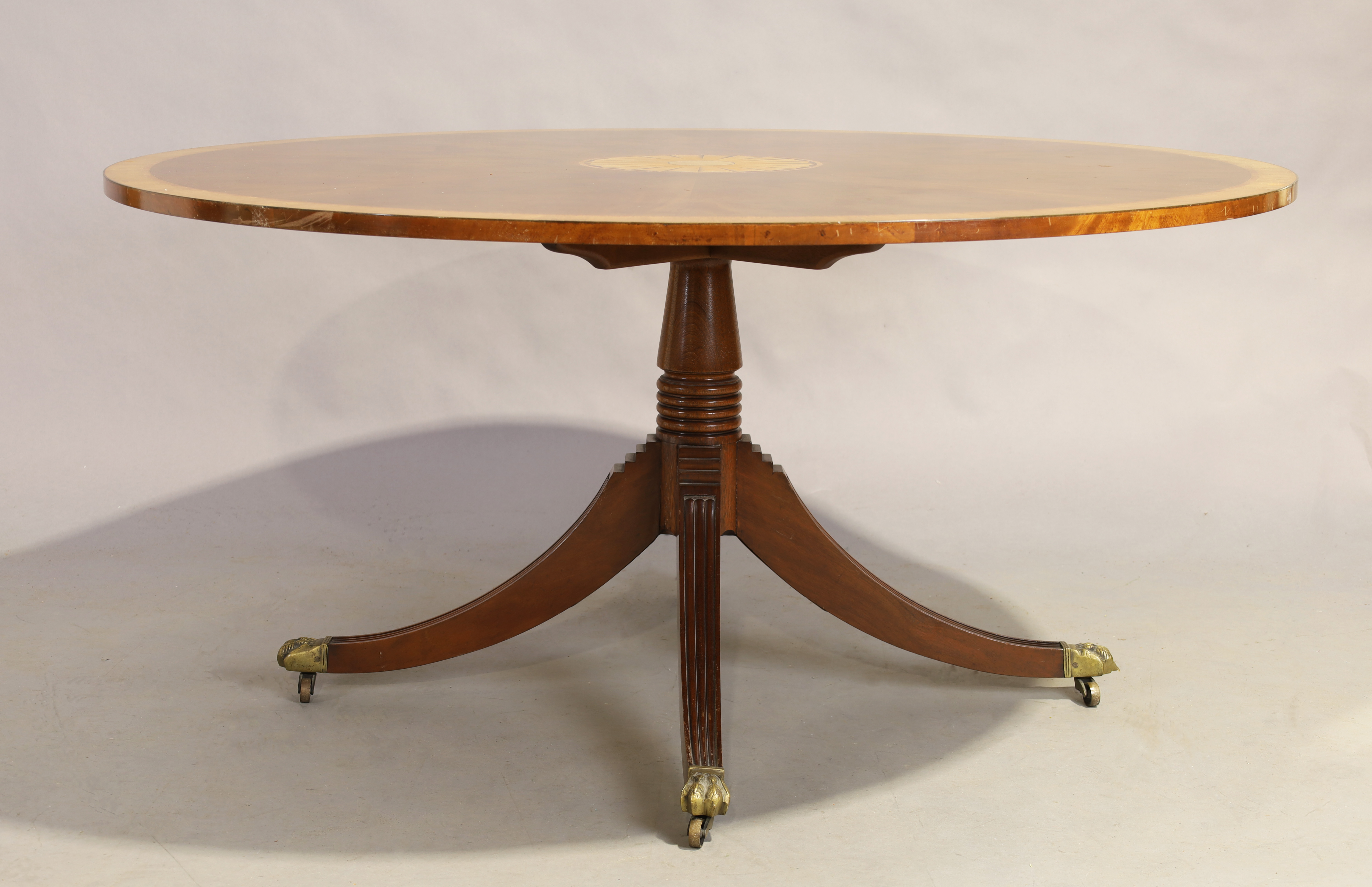 An English mahogany and satinwood crossbanded circular dining table by Restall Brown & Clennell, ...