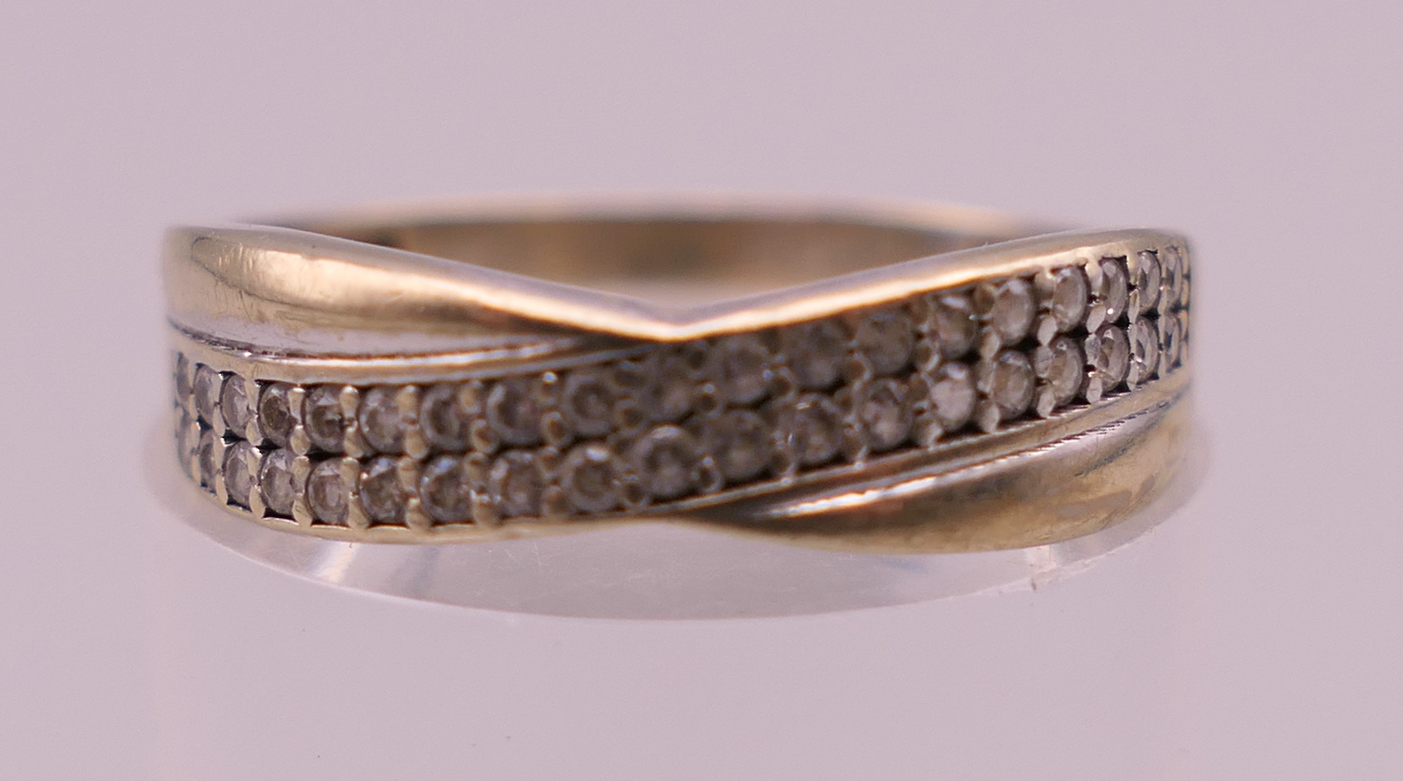 A 9 ct gold diamond set crossover ring. Ring size M. 1.3 grammes total weight.