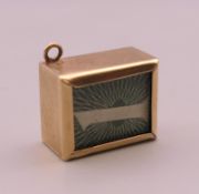 A 9 ct gold charm containing a £1 note. 2.3 grammes total weight.