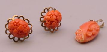A 9 ct gold mounted coral pendant and a pair of earrings. The pendant 2.5 cm high.