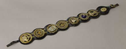 A leather strap of horse brasses. 84 cm long.