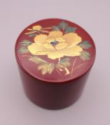 A Chinese cinnabar lacquered scroll weight, inlaid with gilt flower. 5 cm diameter.