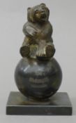 A silver plated inkwell formed as a bear on a ball, inscribed 'With Compliments W.T & H. Miller's'.