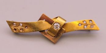 An unmarked gold diamond set knot and bow bar brooch. 5.5 cm wide. 4.8 grammes total weight.