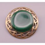 A 9 ct gold and malachite brooch. 3.5 cm diameter. 14.2 grammes total weight.