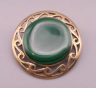 A 9 ct gold and malachite brooch. 3.5 cm diameter. 14.2 grammes total weight.