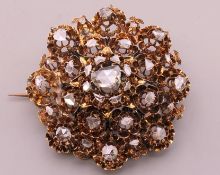 An unmarked pierced gold diamond set brooch. 5 cm diameter. 22.6 grammes total weight.