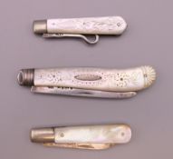 Two mother-of-pearl silver bladed fruit knives and a button hook. The largest 7.5 cm long closed.