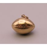 A 9 ct gold rugby ball form charm. 1.5 cm long. 0.7 grammes.