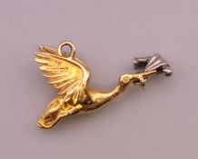 A 9 ct gold charm formed as a stork carrying a baby. 2.6 grammes total weight.