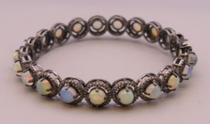 An opal and diamond bangle form bracelet. Interior diameter approximately 6 cm.