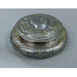 An embossed silver lidded box. 18 cm diameter. 17.4 troy ounces.