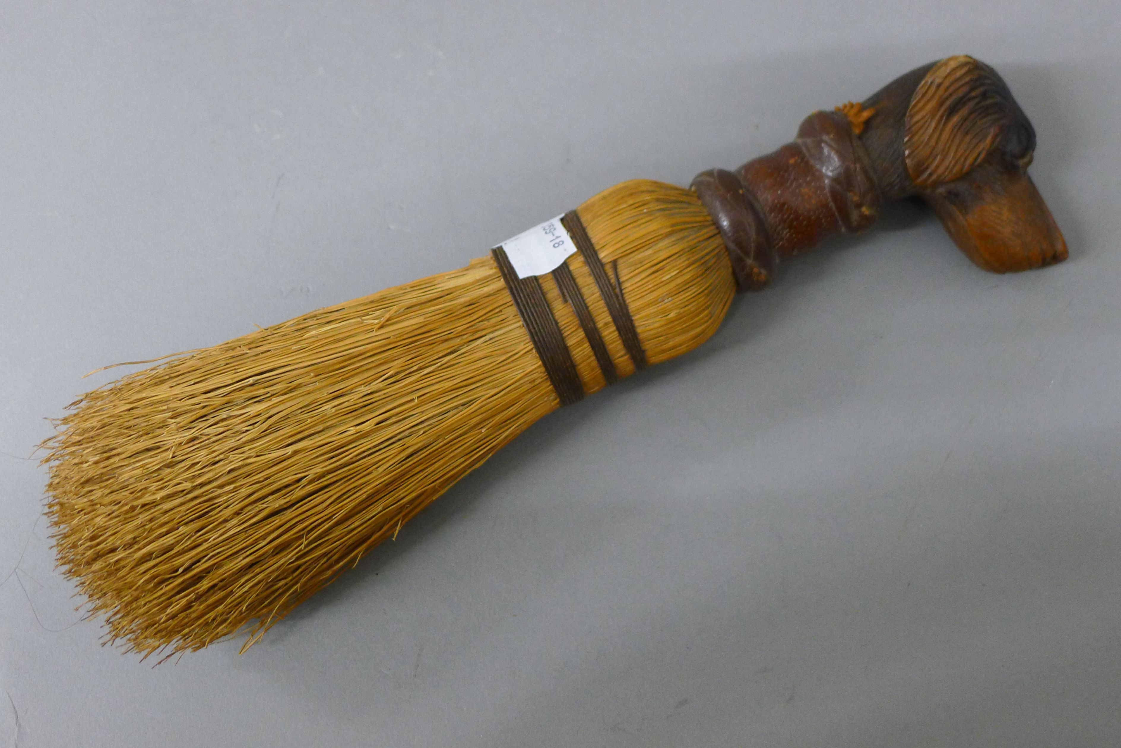 A brush mounted with a carved wooden dog's head handle. 27.5 cm high.
